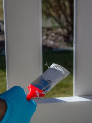 person painting a deck for maintenance